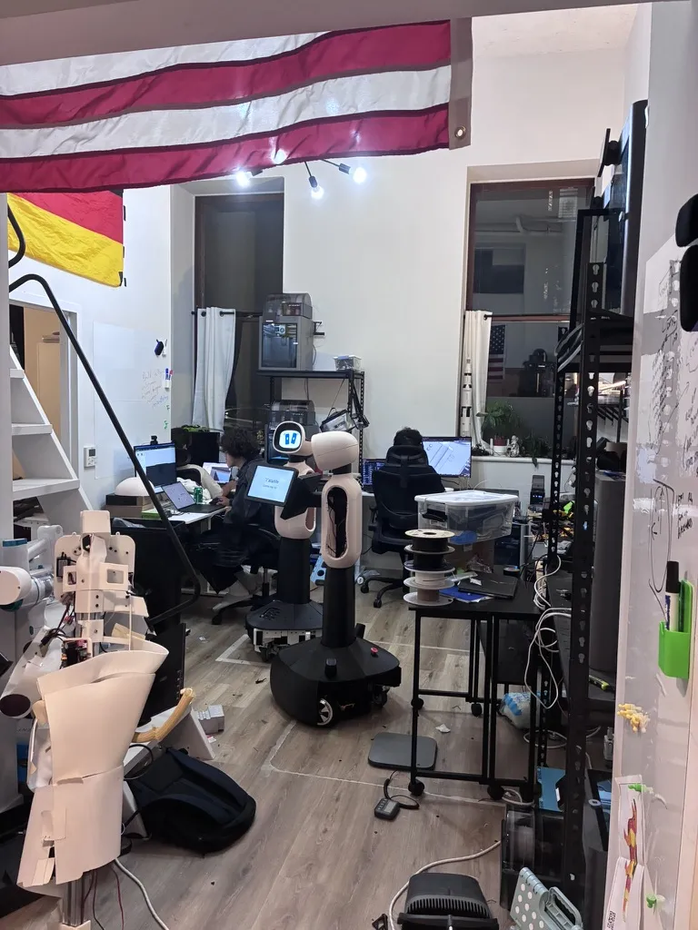 Our hacker house in NYC: robots, parts and desks under an American flag